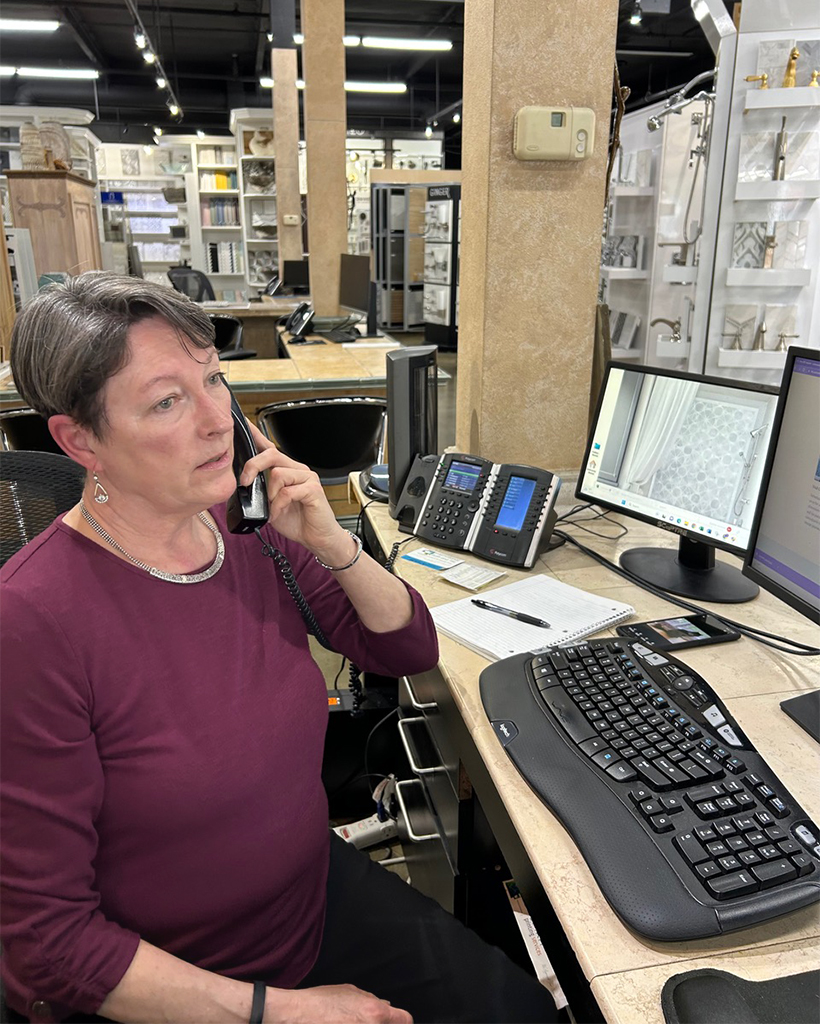 Salesperson sitting on their desk while on the phone